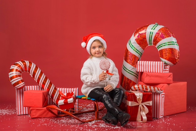 Kostenloses Foto smiley-mädchen umgeben von weihnachtsgeschenken und -elementen