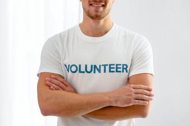 Smiley männlicher Freiwilliger, der mit verschränkten Armen aufwirft