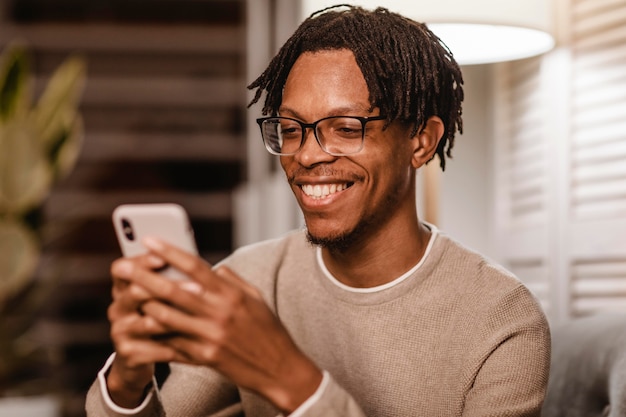 Smiley-Mann, der modernes Smartphone-Gerät zu Hause verwendet