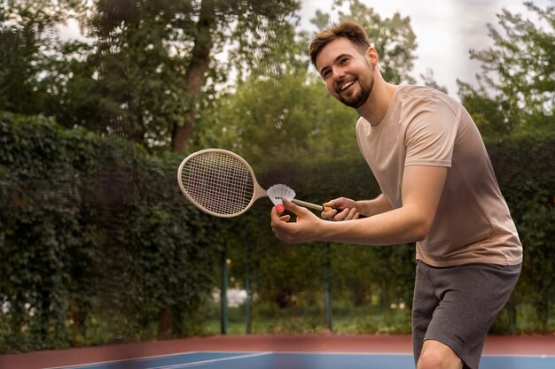 Smiley-Mann der Seitenansicht, der Badminton spielt