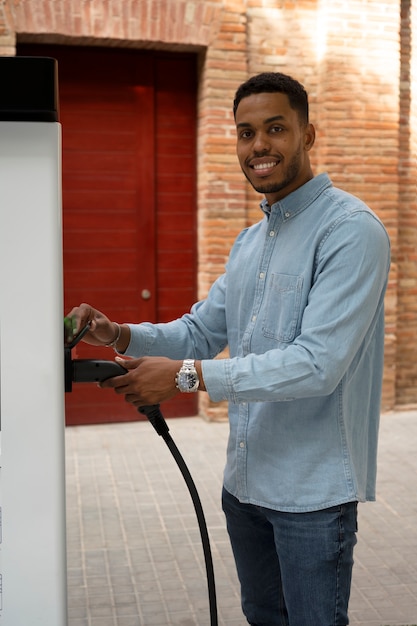 Smiley-Mann der Seitenansicht, der Elektroauto auflädt