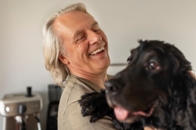 Kostenloses Foto smiley-mann der seitenansicht, der hund hält