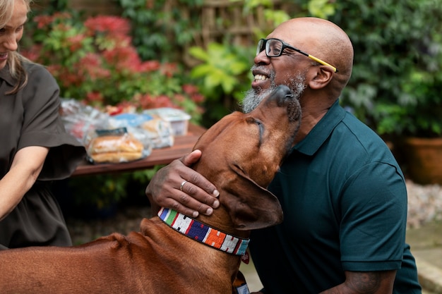 Kostenloses Foto smiley-mann der seitenansicht, der mit hund spielt