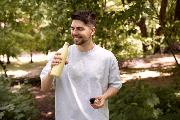 Kostenloses Foto smiley-mann der seitenansicht mit wasserflasche