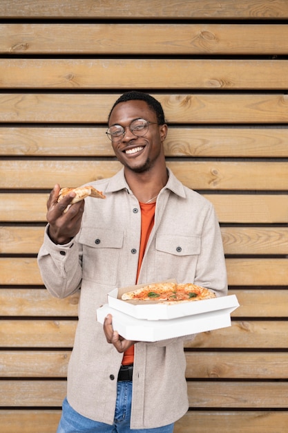 Kostenloses Foto smiley-mann der vorderansicht, der pizza hält