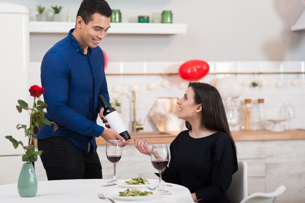 Smiley-Mann der Vorderansicht, der Wein in ein Glas für seine Frau gießt