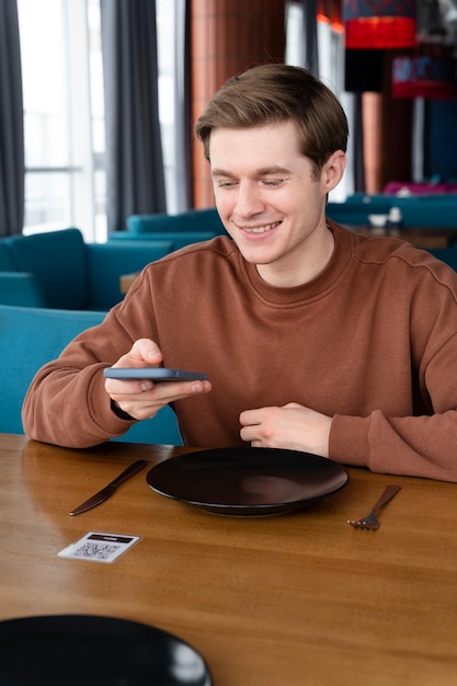 Kostenloses Foto smiley-mann mit mittlerem schuss, der smartphone hält