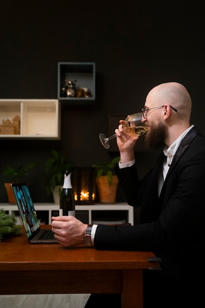 Kostenloses Foto smiley-mann mit mittlerem schuss, der zu hause wein trinkt