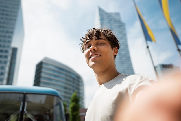 Kostenloses Foto smiley-mann mit niedrigem winkel, der sich im freien selbst macht