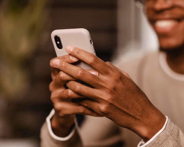 Smiley-Mann zu Hause mit Smartphone