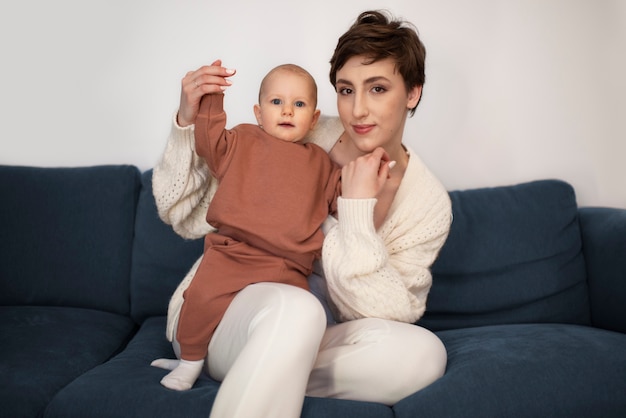 Kostenloses Foto smiley-mutter der vorderansicht auf couch mit baby