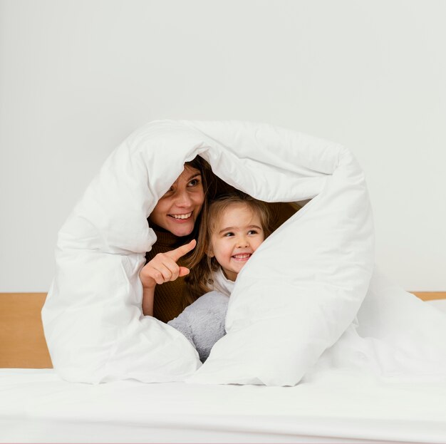 Smiley Mutter und Kind verstecken sich unter der Decke