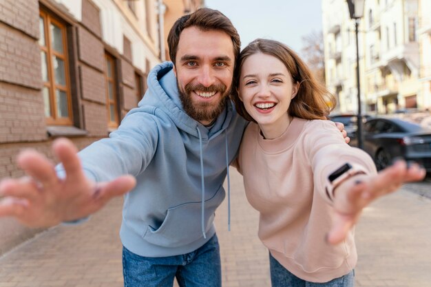 Smiley-Paar macht ein Selfie und gibt vor, nach etwas zu greifen