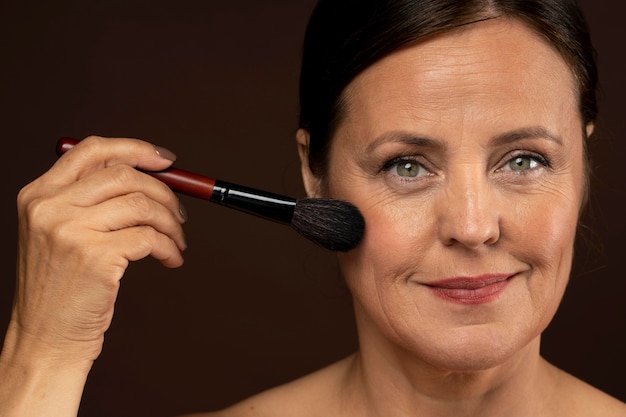 Smiley reife Frau mit Make-up Pinsel auf ihrem Gesicht