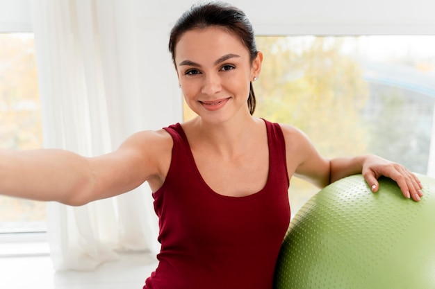 Smiley schwangere Frau, die ein Selfie neben einem Fitnessball nimmt