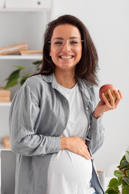 Smiley schwangere Frau, die einen Apfel hält, während zu Hause