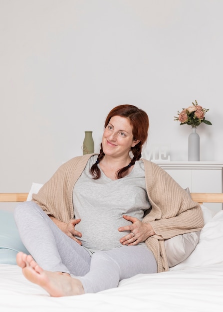 Smiley schwangere Frau im Bett gelegt