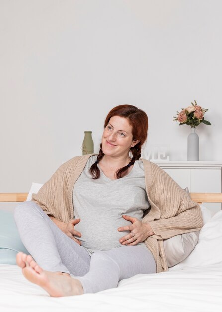 Smiley schwangere Frau im Bett gelegt