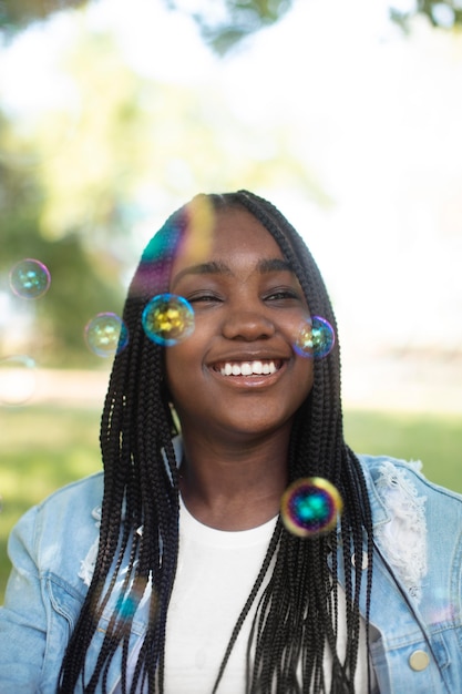 Kostenloses Foto smiley schwarzes teenager-mädchen spielt mit seifenblasen