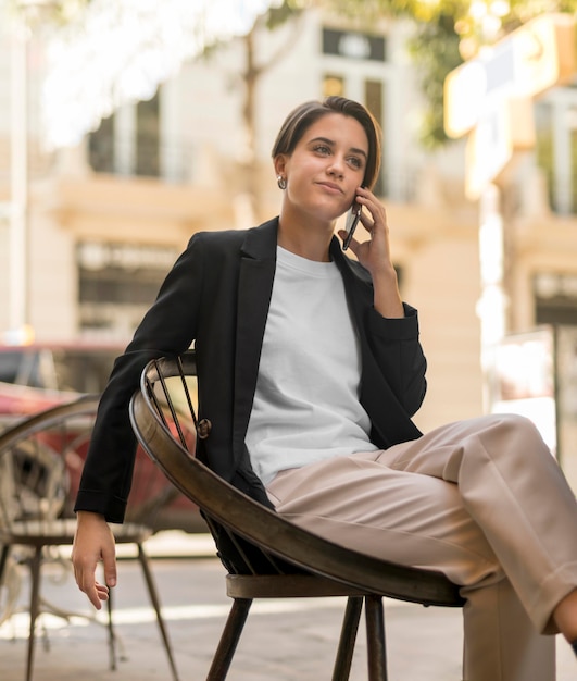 Smiley stilvolle Frau, die draußen am Telefon spricht