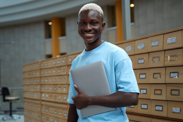 Kostenloses Foto smiley-student mit mittlerem schuss, der laptop hält