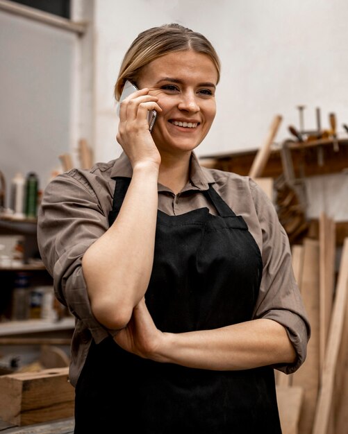 Smiley Tischlerin mit Smartphone bei der Arbeit