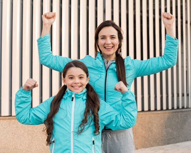 Smiley-Tochter und Mutter zeigen Muskeln