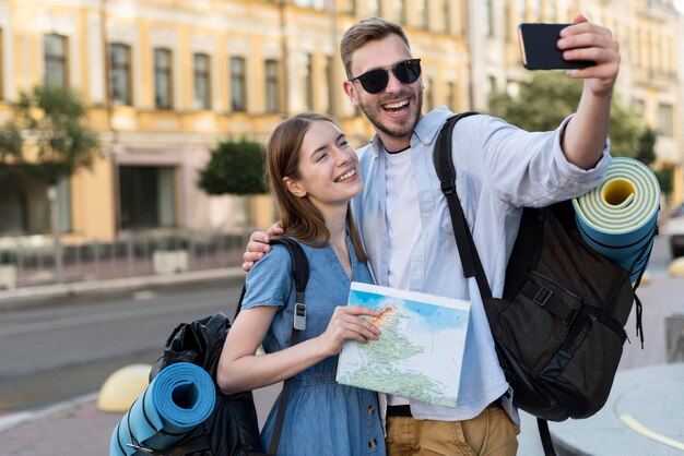 Smiley-Touristenpaar, das Selfie beim Tragen von Rucksäcken nimmt