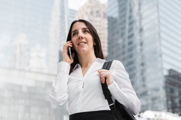 Smileyfrau des niedrigen Winkels, die am Telefon spricht