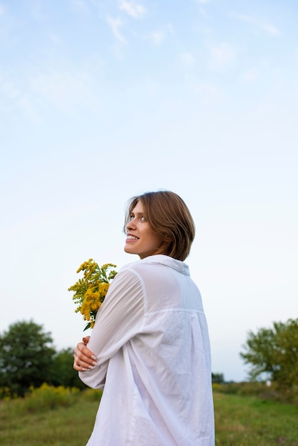 Smileyfrau, die Blumenseitenansicht hält