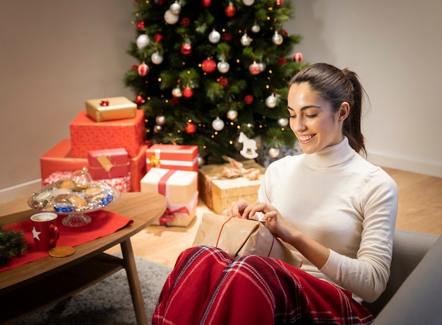 Kostenloses Foto smileyfrau, die ein geschenk auspackt