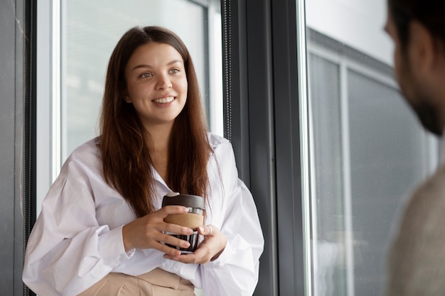 Smileyfrau, die Kaffeetasse bei der Arbeit hält