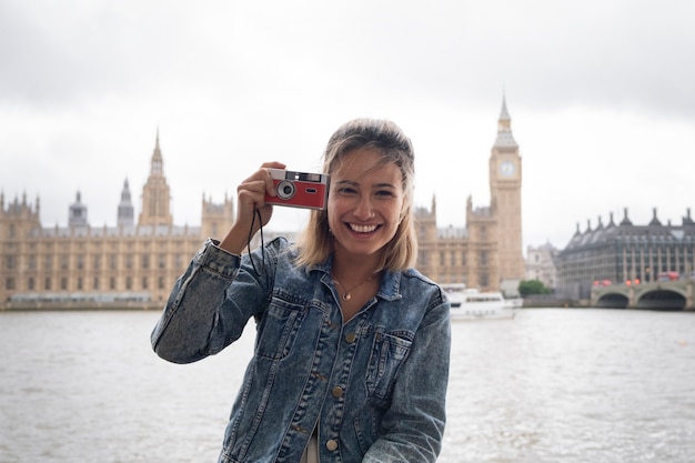 Kostenloses Foto smileyfrau, die vorderansicht der fotokamera hält