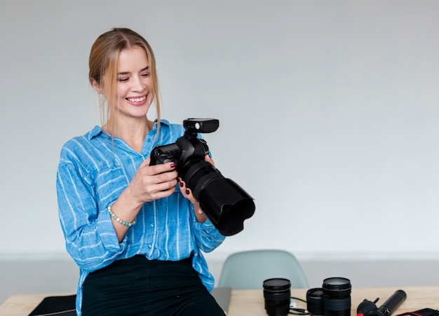 Smileyfrau im blauen Hemd, welches die Fotografiekamera betrachtet