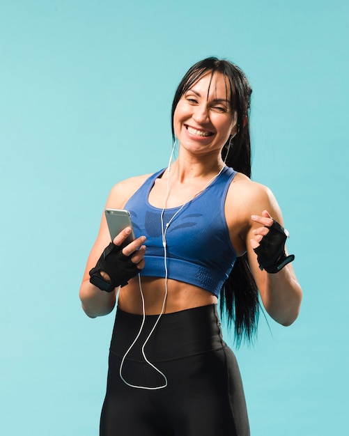 Smileyfrau in der Turnhallenausstattung Musik in den Kopfhörern genießend