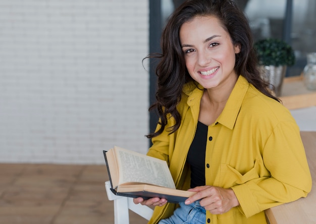 Kostenloses Foto smileyfrau mit dem buch, das kamera betrachtet