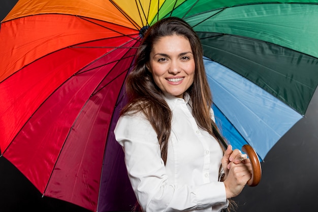 Kostenloses Foto smileyfrau mit dem bunten regenschirm geöffnet