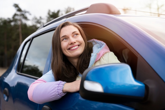 Kostenloses Foto smileyfrau mit mittlerem schuss im auto