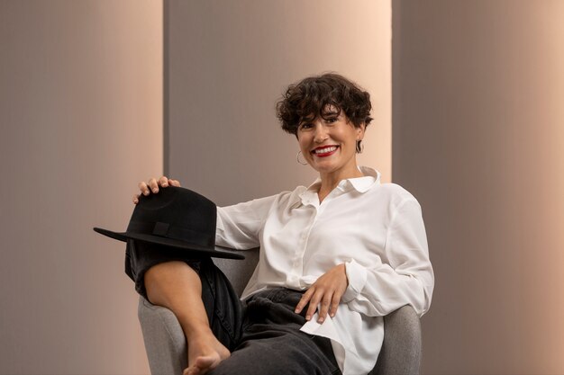 Smileyfrau mit mittlerer Aufnahme, die auf Stuhl sitzt