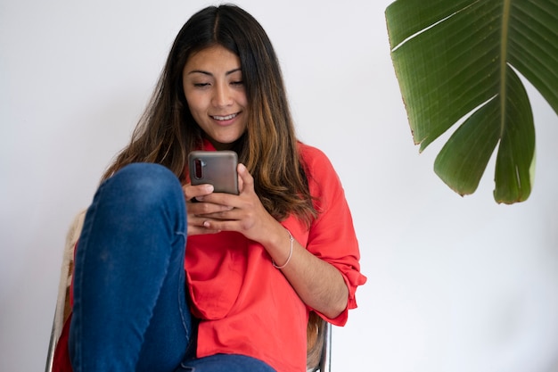 Smileyfrau mit mittlerer Aufnahme, die auf Stuhl sitzt