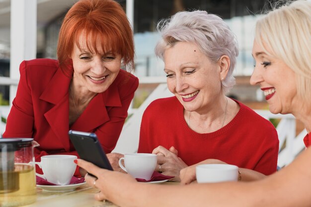 Smileyfrauen, die ein Telefon betrachten