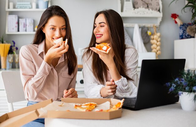 Smileyfrauen, die Pizza nach der Arbeit essen