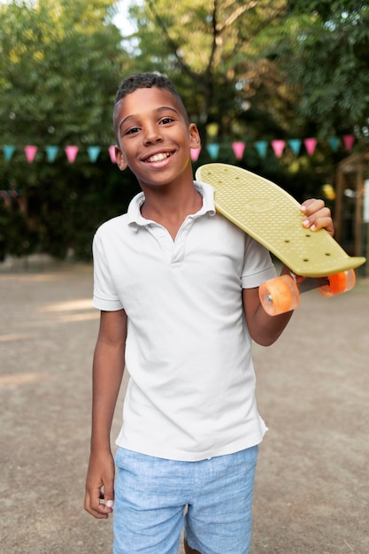 Smileyjunge mit mittlerem Schuss, der ein Penny Board hält