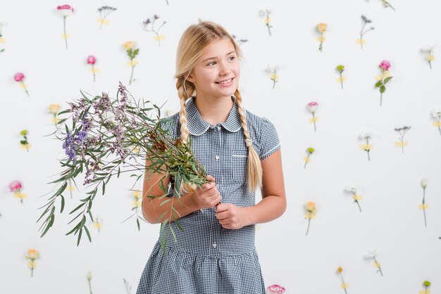 Smileymädchen, das Blumenstrauß von Blumen hält