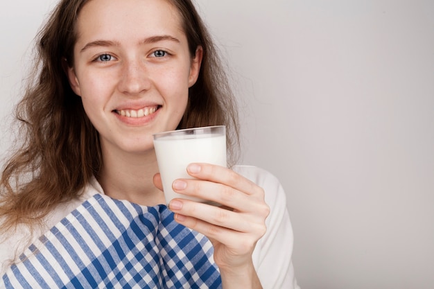 Smileymädchen, das ein Glas Milch mit Kopienraum hält