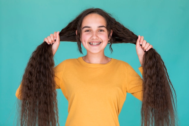 Kostenloses Foto smileymädchen, das ihr langes haar hält