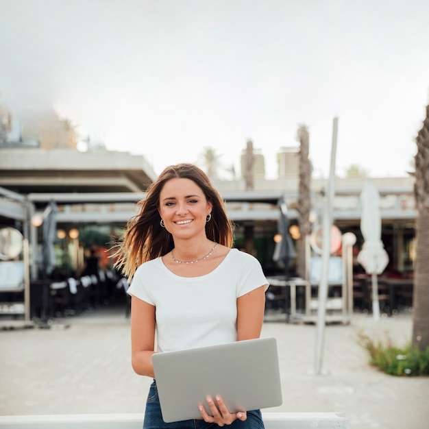 Smileymädchen mit dem Notizbuch, das Kamera betrachtet