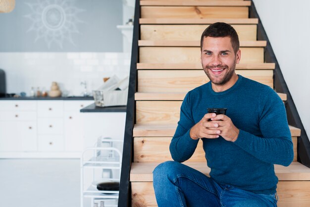 Smileymann, der Kamera betrachtet und einen Tasse Kaffee hält