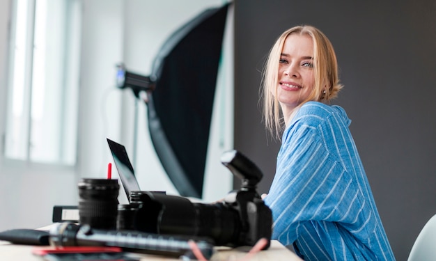 Kostenloses Foto smileyphotographfrau, die an ihrem schreibtisch sitzt