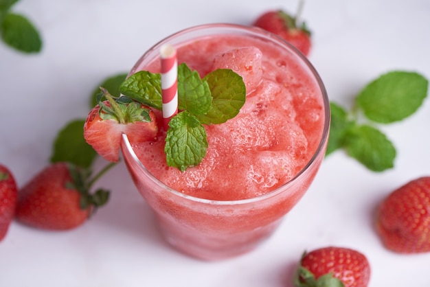 Smoothies Sommererdbeere trinken, Köstlicher Erdbeersmoothie garniert mit frischer Erdbeere und Minze im Glas. Weicher Fokus. schöne Vorspeise rosa Erdbeere, Wohlbefinden und Gewichtsverlustkonzept